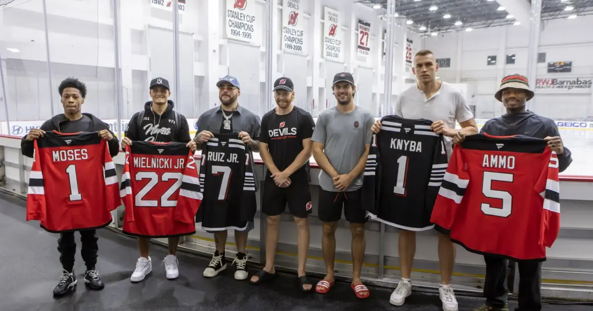 Andy Ruiz and Damian Knyba with main card fighters holding New Jersey Devils Jerseys